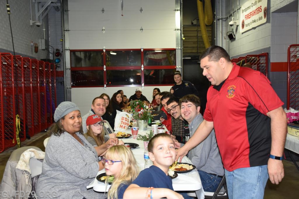 The members and families enjoying their holiday meal while waiting for Santa Claus to arrive