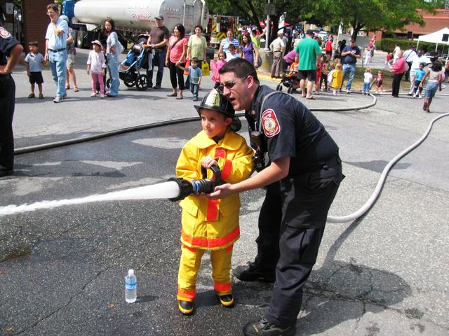 Firefighter Dinowitz helps a young firefighter with the hose line.