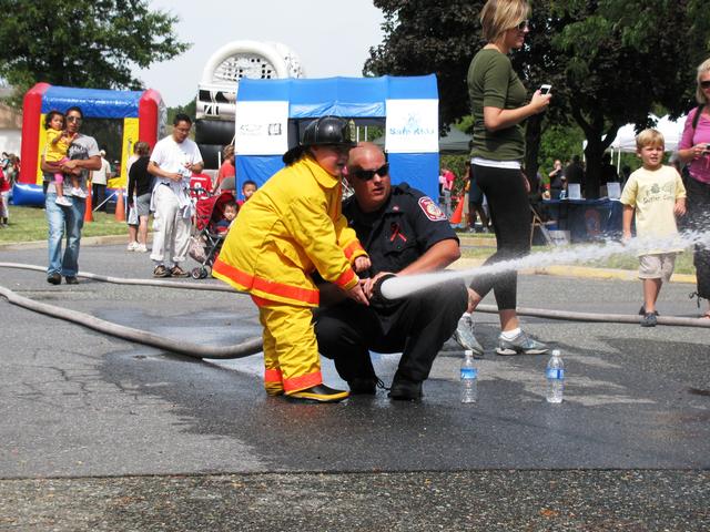 Firefighter Younkins teaches a future firefighter how to get the stream through the window.